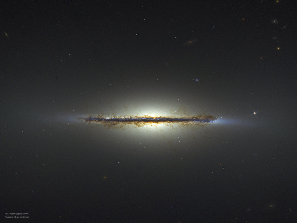 A starfield is shown with an unusual horizontal line 
segment running throug the middle. The segment is an
edge-on galaxy and many brown dust filaments are visible.
Please see the explanation for more detailed information.